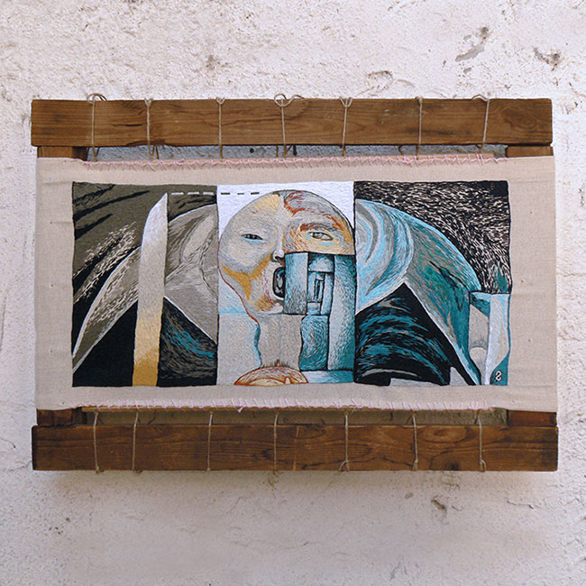 Embroidered, expressive, and symbolic artwork stretched on a wooden frame against a white wall.