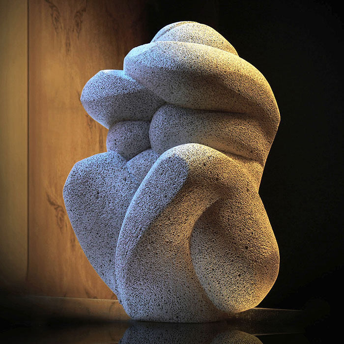 White sculpture of a softly lit, stylized woman against a mysterious background.